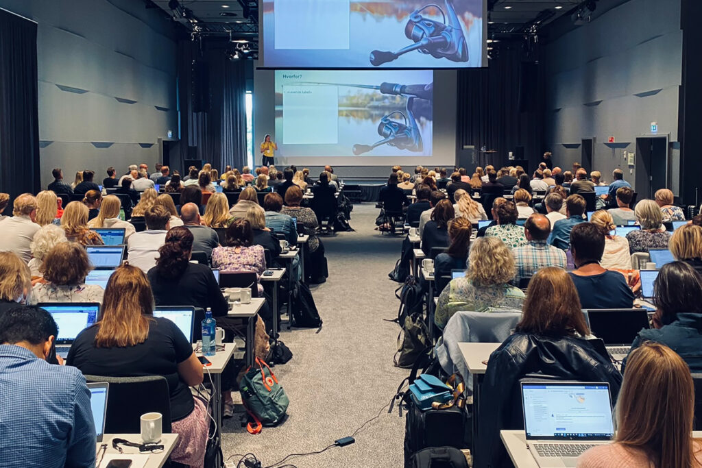 Mange mennesker i en konferansesal som ser på et foredrag fra Framsikt Systemansvarligsamling