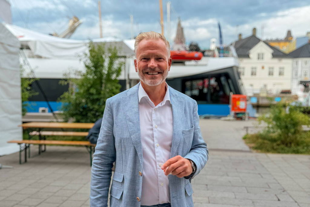 En mann som står ute på gaten og smiler til kameraet.